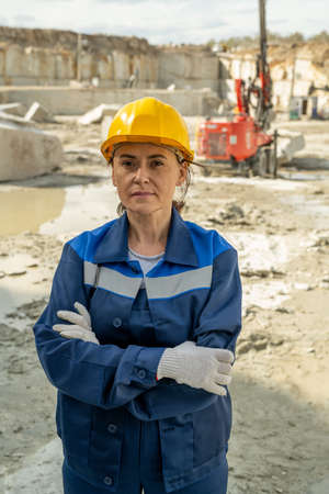 Young serious female builder in workwear standing at building placeの写真素材