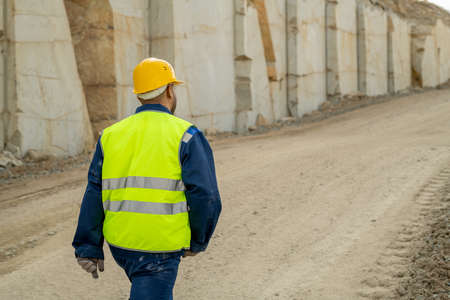 Back view of young builder in workwear moving along construction site