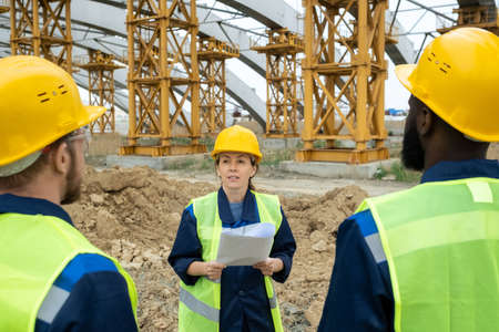 Female engineer in workear talking to her male colleagues at meetingの写真素材