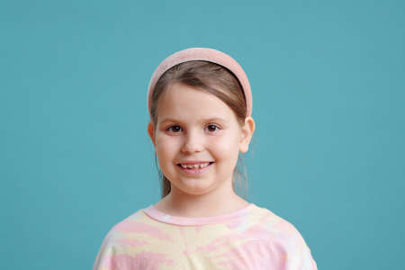 Cute little girl with toothy smile over blue backgroundの写真素材
