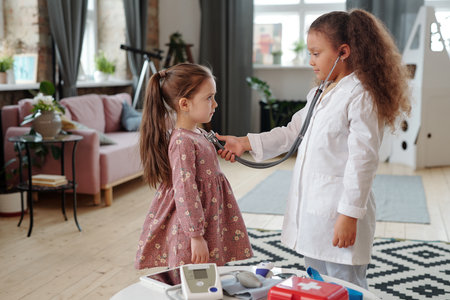 Two adorable little girls playing doctor in home environmentの写真素材
