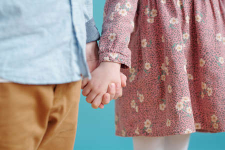Two little kids in casualwear holding by handsの写真素材