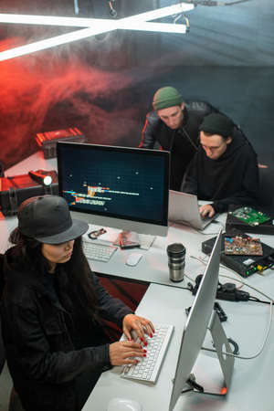 Young woman and two guys decoding and stealing important informationの写真素材