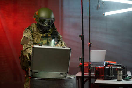 Gloved criminal with lantern committing cyber crime in the dark office
