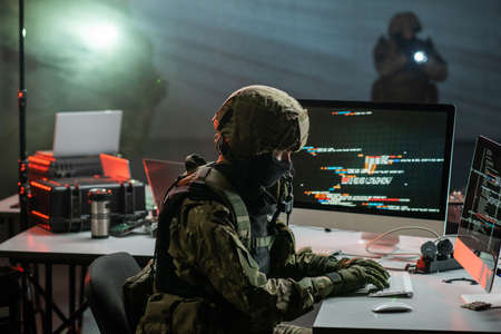 Gloved cyber criminal in camouflage attire decoding or stealing informationの写真素材