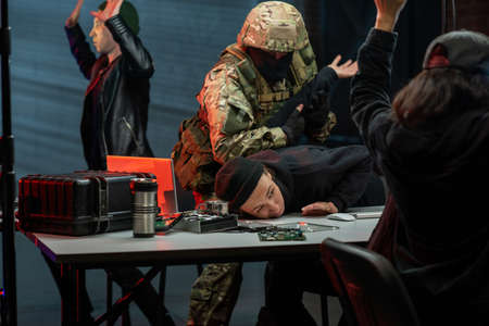 Military men in camouflage outfit capturing cyber criminals in officeの写真素材