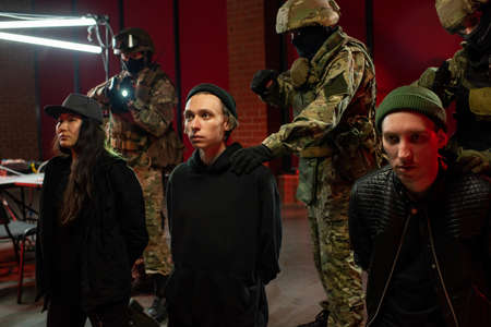 Three arrested cyber criminals with officers in military outfit behind