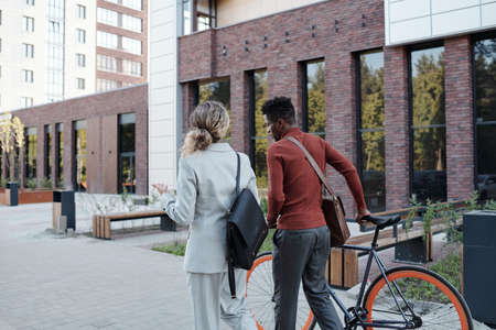Rear view of two colleagues moving along park in urban environmentの写真素材