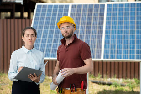 Portrait of manager and mounter standing in backyard with solar panels in background