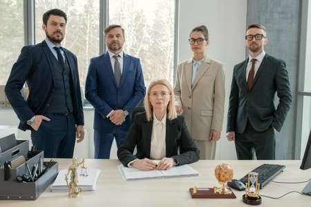 Portrait of successful business team with their leader looking at camera while working in team at...