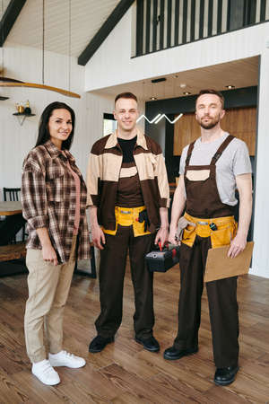 Female client and two repairmen in workwear standing in front of cameraの写真素材