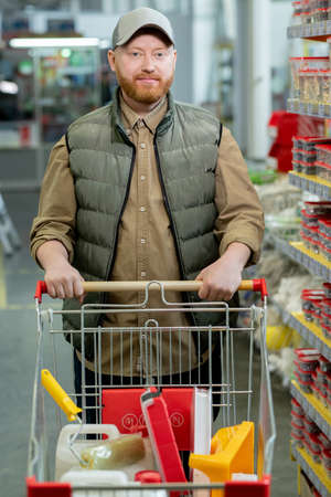 Male customer pushing cart with chosen household goodsの写真素材