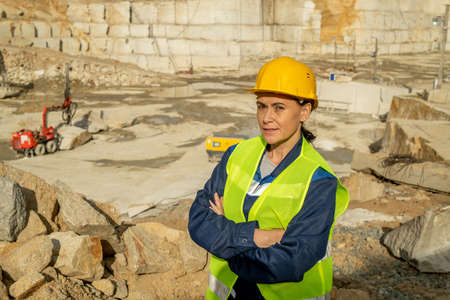 Serious and confident female builder in workwear standing against construction siteの写真素材