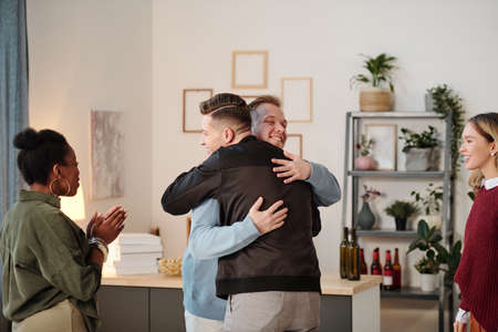 Two young happy men in casualwear standing in front of one another during arm wrestling at home...