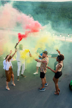 Contemporary young ecstatic people dancing on patio while enjoying rooftop party