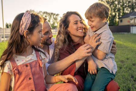 Cheerful young parents playing with their two adorable kids outdoors