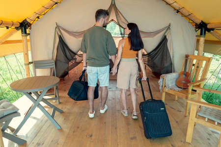 Caucasian couple of travelers entering bedroom of glamping house after arriving in resort areaの写真素材