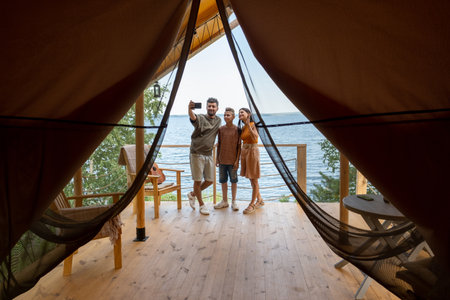 Happy family looking at smartphone screen while communicating with friends through video chatの写真素材