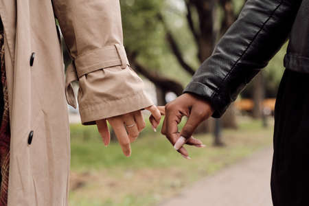 Hands of amorous intercultural girlfriends taking walk in park at leisureの写真素材