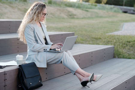 Young contemporary businesswoman with laptop networking in urban environmentの写真素材