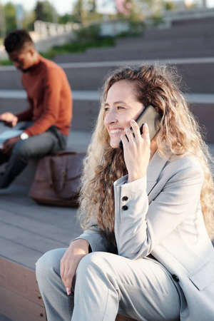 Happy young woman talking on smartphone against African businessman