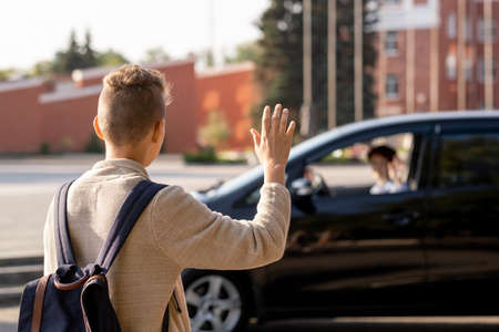 Schoolboy saying goodbye to his mom in the car before going to school in the morningの写真素材