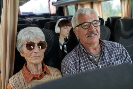 Content senior Caucasian couple with gray hair sitting in bus while travelling togetherの写真素材
