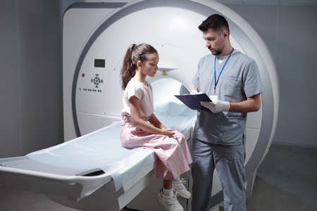 Serious radiologist making prescription to little girl after MRI scan examinationの写真素材