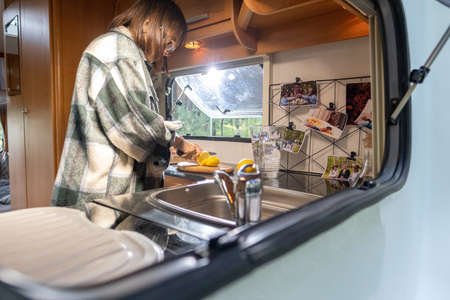 Young female slicing lemon on wooden board in the kitchen of travel houseの写真素材