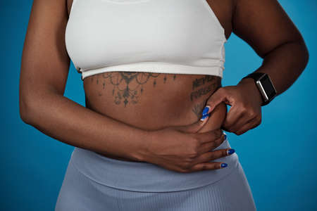 Midsection of body of African plus size female against blue backgroundの写真素材