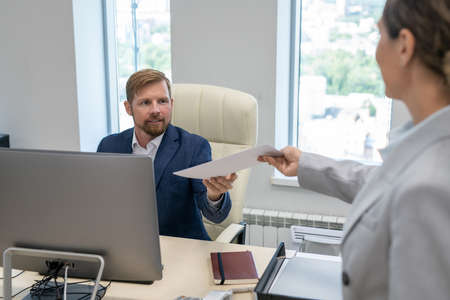 Young businessman taking financial papers given by his female colleague or secretaryの写真素材