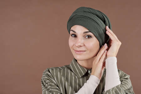 Horizontal medium close-up studio portrait of beautiful Muslim woman wearing fashionable striped...