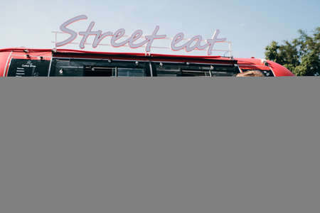 Young couple interacting while having fast food in outdoor cafe against street truckの写真素材