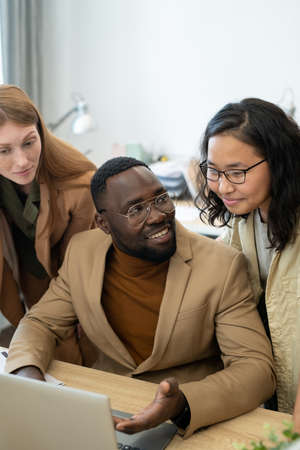 Group of young intercultural employees discussing presentation in front of laptopの写真素材