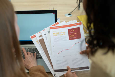 Papers in hands of young female economist during teamwork with colleagueの写真素材