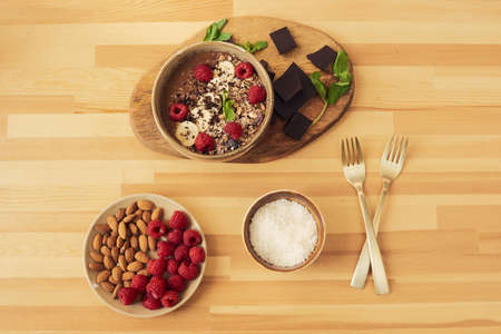Bowl with dessert and ingredients which it contains on wooden kitchen table
