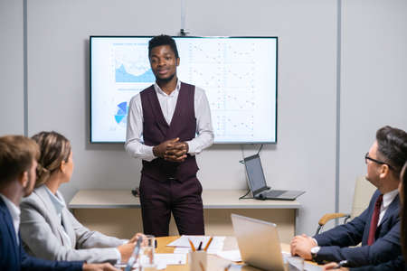 Young successful business coach standing in front of audience during speech by whiteboardの写真素材