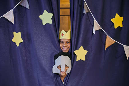 Portrait of children in costumes smiling at camera hiding behind the scenes, they acting in performanceの写真素材