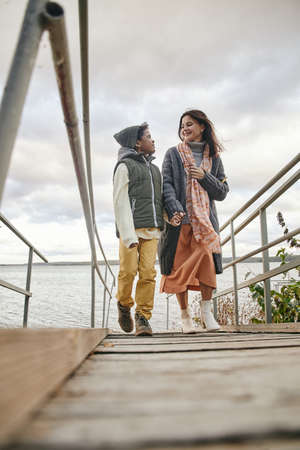 Happy young mother talking to her son while they walking together on the nature in autumn day