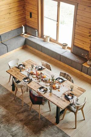 High angle view of dining table decorated with autumn branches and beautiful service standing in big...