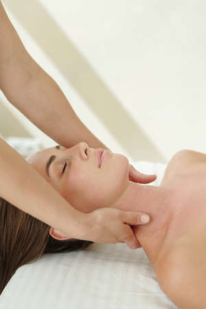 Young woman enjoying massage of neck being done by masseuse of contemporary spa resort or center