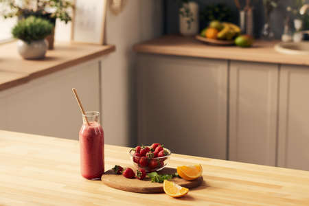 Fresh ingredients for fruit homemade smoothie and bottle with the drink or dessert on wooden table in kitchen environmentの写真素材