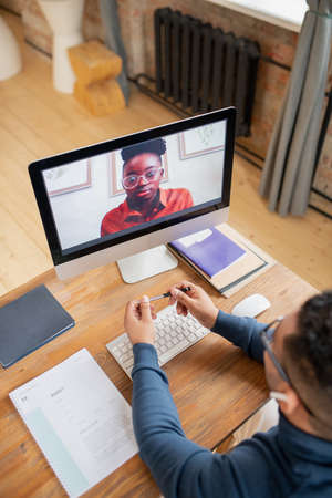 Young African female student on computer screen looking at her teacher during online consultation or...