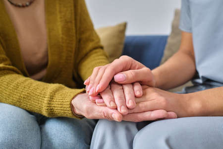 Close-up of nurse holding hands of senior woman, she supporting and caring about her during diseaseの写真素材