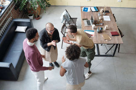 Several happy young office workers having fun at break while standing in circle between black...