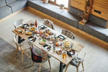 Several chairs around large wooden dining table served with homemade food for festive dinner in living-roomの写真素材