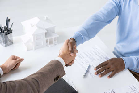 Directly above view of unrecognizable blackman handshaking with bank specialist after signing loan...