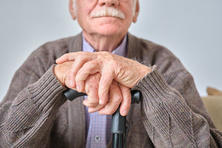Close-up of elderly man with white moustache sitting leaning on his crutchの写真素材
