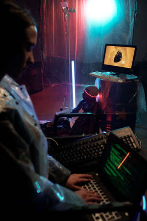 Young female typing on computer against African male cyberpunk with illumination around his headの写真素材