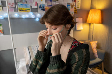 Young woman wearing the oxygen tube on her face while sitting in her hospital ward during pandemic